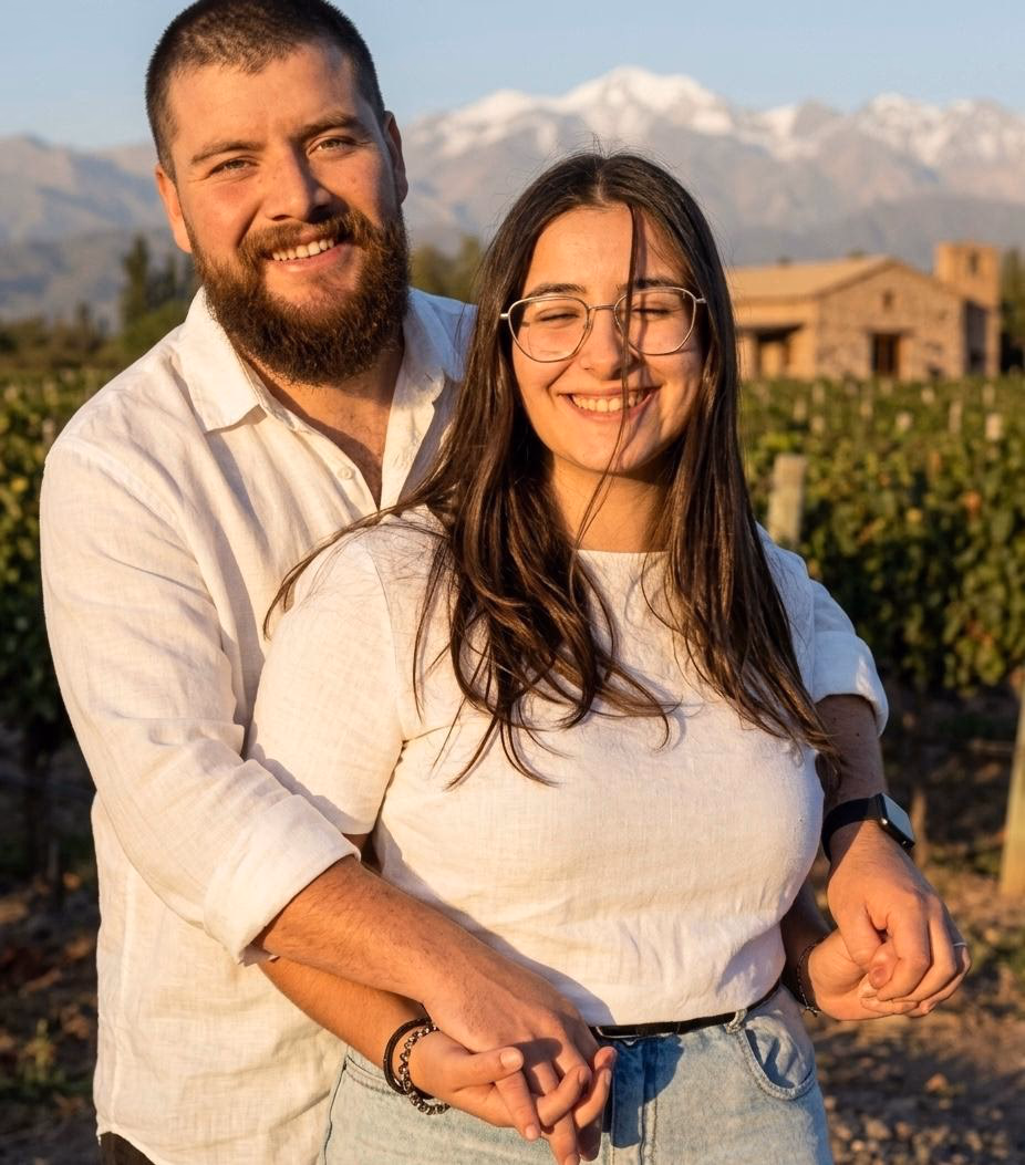 Lourdes y Nicolás abrazados en la viña, con la cordillera nevada de fondo